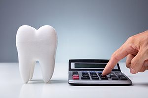 Tooth next to calculator; figuring out cost of emergency dentist in Lakewood, CO 