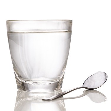 Clear glass of water next to spoon full of salt