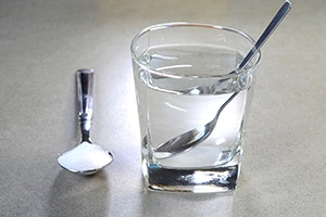 Glass of water next to spoon full of salt