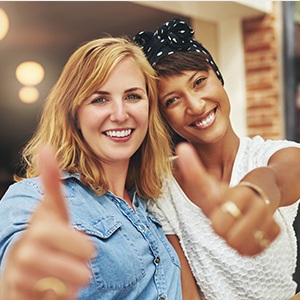 Two smiling women giving thumbs up