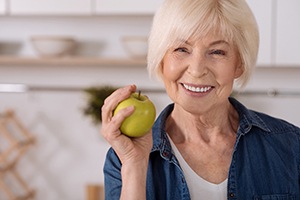 An older woman holding a green apple