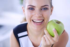 Woman with healthy smile holding an apple