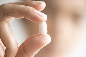 Hand holding white antibiotic pill