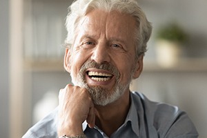 An older man smiling after receiving his customized dental implants
