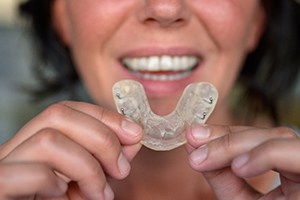 A woman suffering from bruxism prepares to insert a customized mouthguard