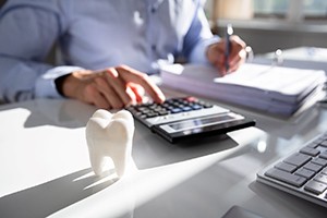Implant dentist in Lakewood calculating costs of dental implant treatment