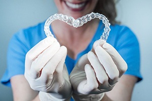 dental team member holding two aligners in the shape of a heart