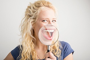 Woman smiling with magnifying glass and teeth whitening in Lakewood