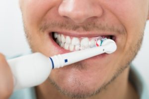 man with facial hair using electric toothbrush