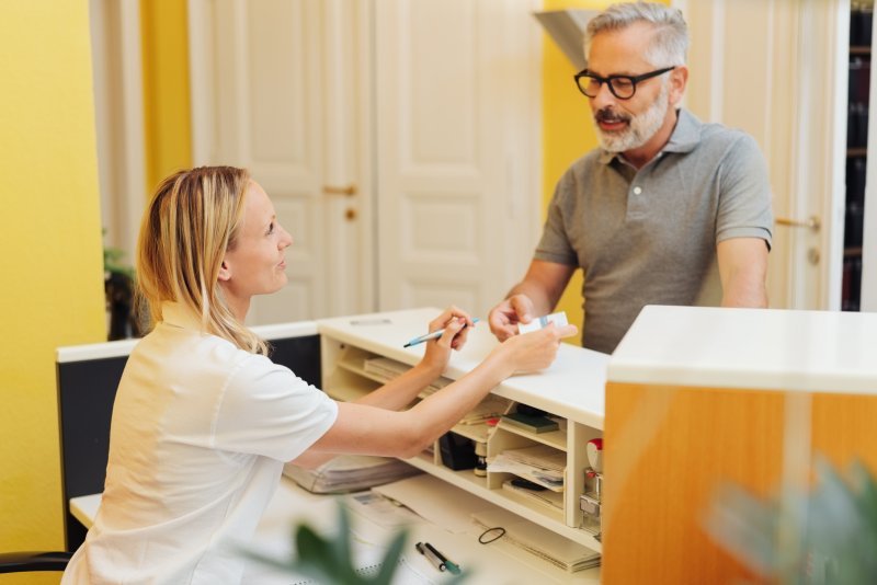 Patient learning the cost of dental work from dental employee.