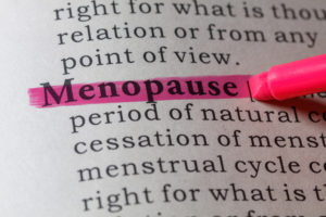 a person highlighting the definition of menopause in a dictionary