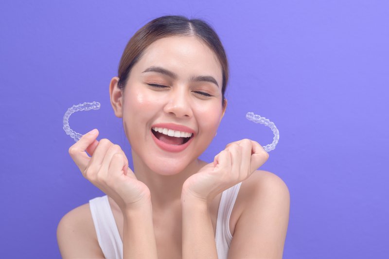 young woman holding an Invisalign aligner