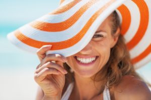 a woman showing her beautiful smile with veneers on the beach