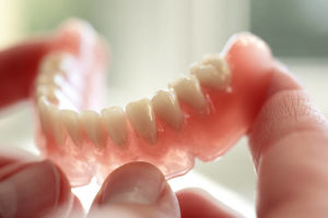 Lower denture held by fingertips