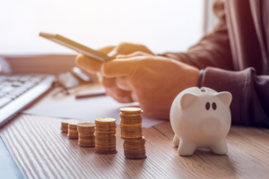 Patient sitting at their desk with a calculator and piggy bank