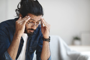 Man with glasses suffering a headache