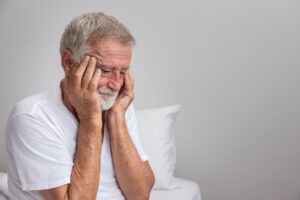 An older man holding his head and appearing worried